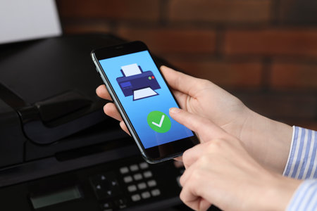Man using printer management application on mobile phone indoors, closeup. Image on device screen.の写真素材