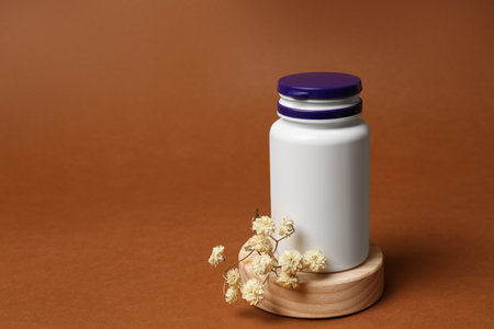 Medicine bottle near gypsophila flowers on brown background, space for textの写真素材
