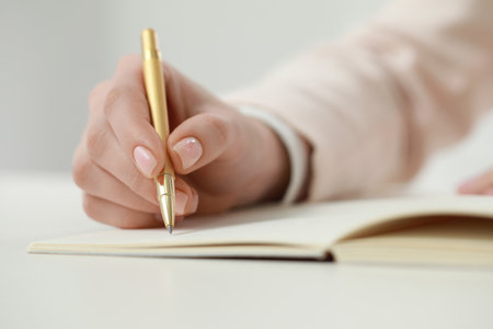 Woman writing in notebook at white table, closeupの写真素材