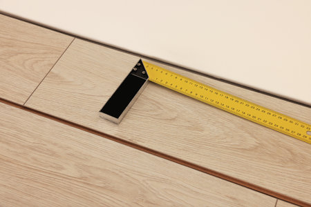 Ruler and parquet planks on floor in room