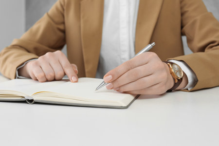 Woman writing in notebook at white table, closeupの写真素材