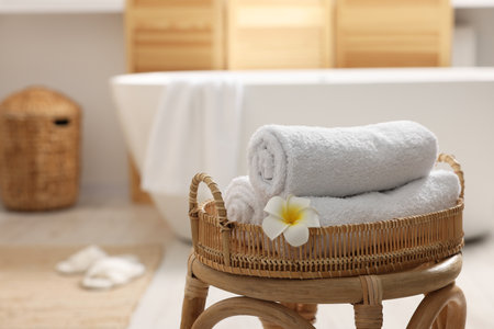 Rolled towels on wicker stool in the bathroom. Space for textの写真素材