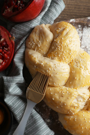 Homemade braided bread and ingredients on wooden table, flat lay. Cooking traditional Shabbat...