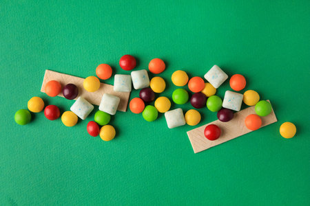 Different tasty chewing gums on green background, flat layの写真素材