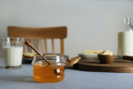 Jar with honey, milk and butter served for breakfast on gray tableの写真素材