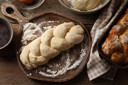 Raw braided bread and ingredients on wooden table, flat lay. Traditional Shabbat challahの写真素材