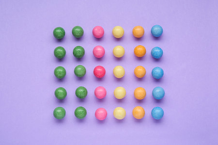Many bright chewy gumballs on lilac background, flat layの写真素材