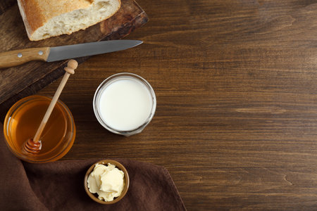 Flat lay composition of honey, milk and butter on wooden table. Space for textの写真素材
