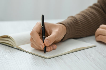 Man writing in notebook at white wooden table, closeupの写真素材