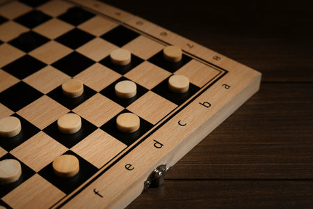 Checkerboard with game pieces on wooden table, closeupの写真素材