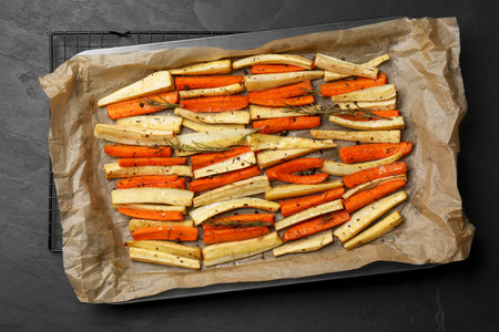 Tray with baked parsnips and carrots on black table, top viewの写真素材