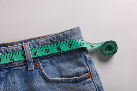 Jeans with measuring tape on light gray background, top view. weight loss conceptの写真素材