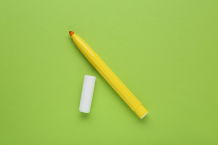 Bright yellow marker and cap on light green background, flat layの写真素材