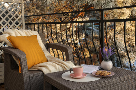 Cup with tasty cocoa, cookies and book on rattan table at balconyの写真素材