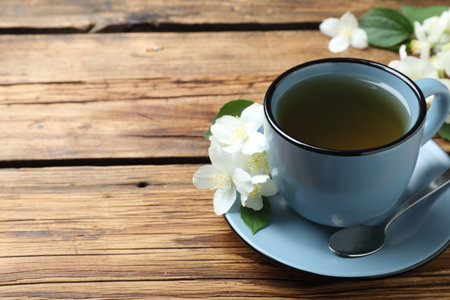 Cup of tea and fresh jasmine flowers on wooden table. Space for textの写真素材