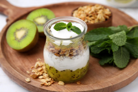 Delicious dessert with kiwi, yogurt and muesli on wooden board, closeupの写真素材