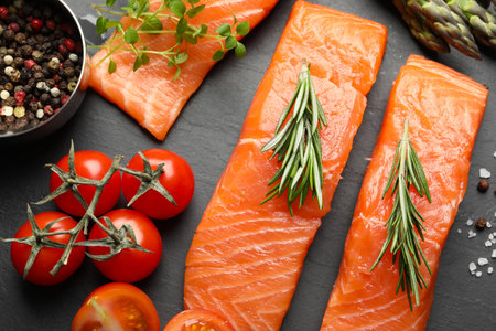 Fresh raw salmon and ingredients for marinade on black table, flat lay