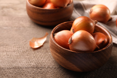 Many ripe onions on wooden table, closeup. Space for textの写真素材