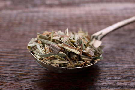 Metal spoon with aromatic dried lemongrass on wooden table, closeupの写真素材