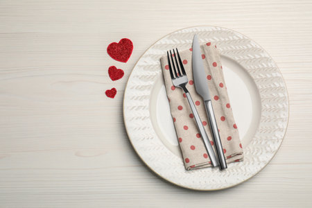 Plate with cutlery and decorative hearts on white wooden table for romantic dinner, top view. Space for textの写真素材