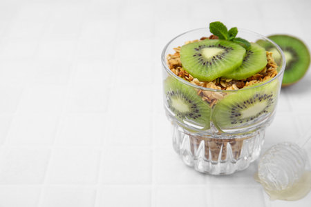 Delicious dessert with kiwi and muesli on white table, closeup. Space for textの写真素材