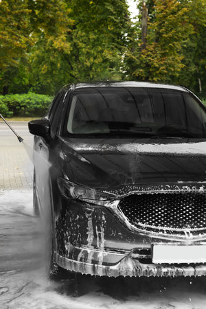 Washing auto with high pressure water jet at outdoor car washの写真素材