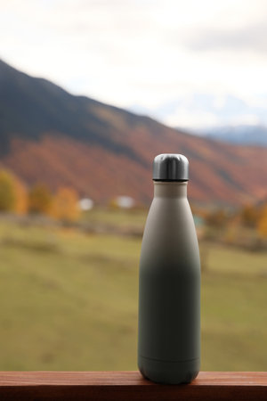 Thermo bottle on wooden surface in beautiful mountainsの写真素材