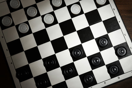 Checkerboard with game pieces on wooden table, top viewの写真素材
