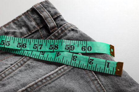 Jeans with measuring tape on light gray background, top view. weight loss conceptの写真素材