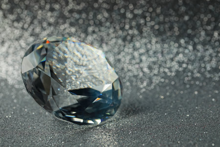Beautiful dazzling diamond on shiny glitter background, closeup. Space for text