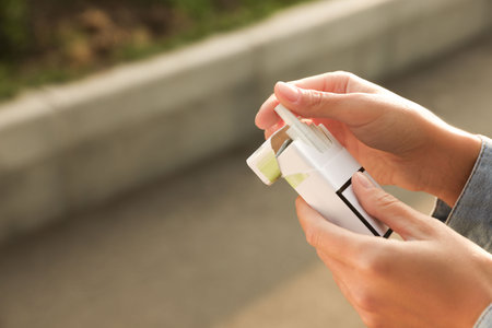Woman taking cigarette out of pack outdoors, closeup. Space for text