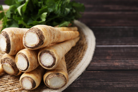 Raw parsley roots and fresh herb on wooden table, closeup. Space for textの写真素材