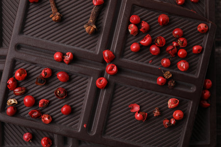 Texture of delicious chocolate bar with red peppercorns as background, top view