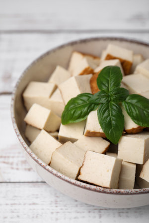 Bowl with delicious fried tofu and basil on white wooden tableの写真素材