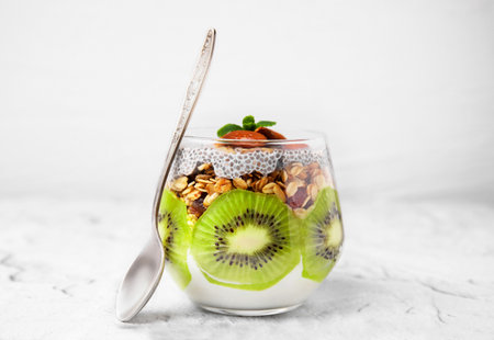 Delicious dessert with kiwi, chia seeds and spoon on light textured tableの写真素材