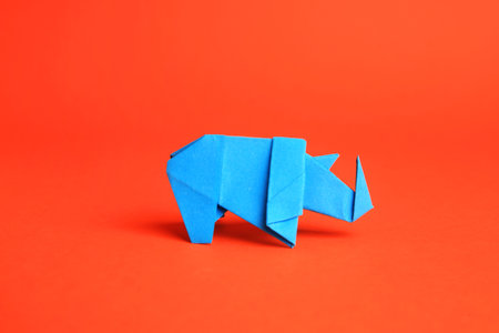 origami art. Handmade light blue paper rhinoceros on orange backgroundの写真素材