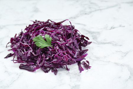 Tasty red cabbage sauerkraut with parsley on white marble table. Space for text
