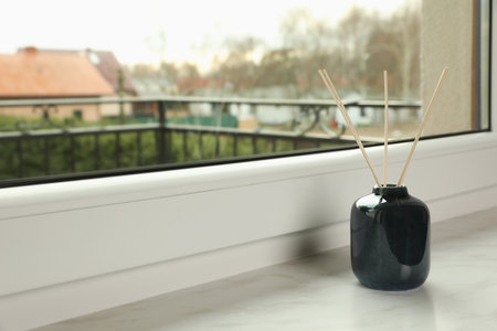 Aromatic reed air freshener on windowsill indoors, space for textの写真素材
