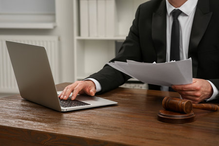law and justice. Lawyer working with documents and laptop at wooden table in office, closeupの写真素材
