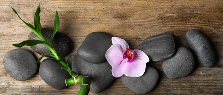 spa treatments. Flat lay composition with stones, bamboo and orchid flower on wooden table. banner designの写真素材