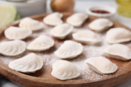Raw dumplings (varenyky) with tasty filling and flour on wooden board, closeupの写真素材