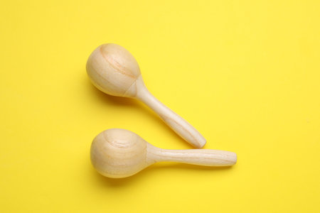 Wooden maracas on yellow background, flat lay. musical instruments