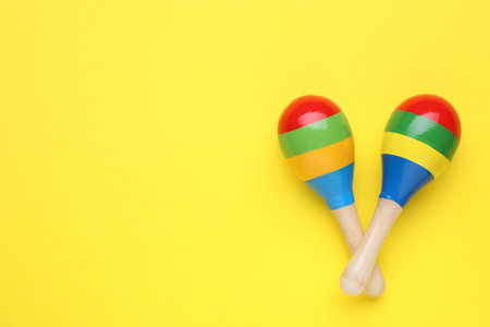 Colorful maracas on yellow background, flat lay with space for text. musical instruments