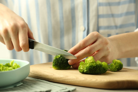 Woman cutting boiled broccoli at table, closeup. child's foodの写真素材
