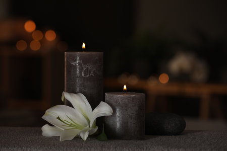 Spa composition with burning candles, lily flower and stone on massage table in wellness centerの写真素材