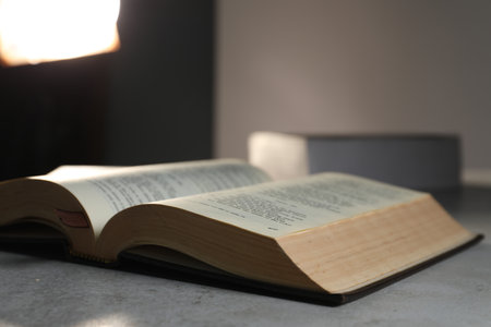 Closeup view of open hardcover Bible on gray table indoors, space for text. religious bookの写真素材