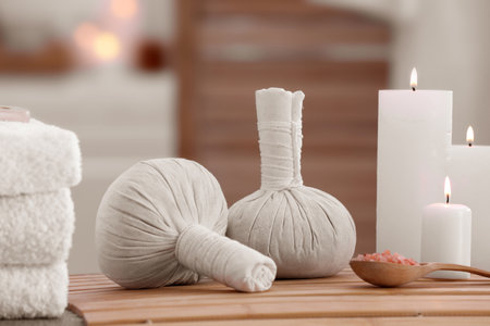 Spa composition with burning candles and herbal bags on massage table in wellness centerの写真素材