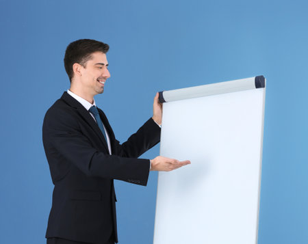 Business trainer giving presentation on flip chart board against color backgroundの写真素材