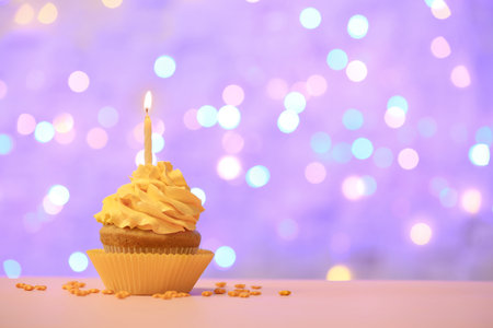 Birthday cupcake with candle against blurred lightsの写真素材