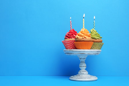 Birthday cupcakes with candles on stand against color backgroundの写真素材